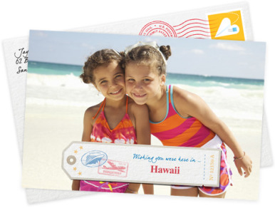 A photo card of two girls on a beach reading “Wishing you were here in Hawaii,” with a stamped envelope