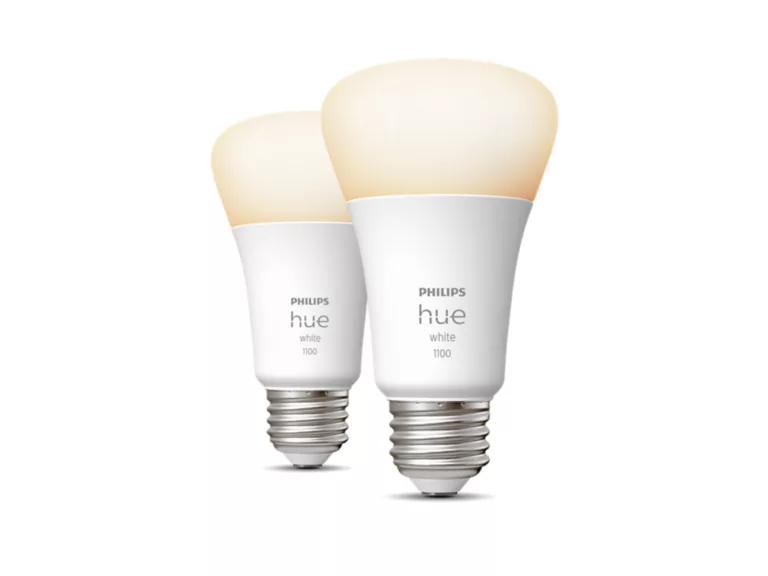 Two white Philips Hue White 1100 smart bulbs, lit with a warm glow, side by side.