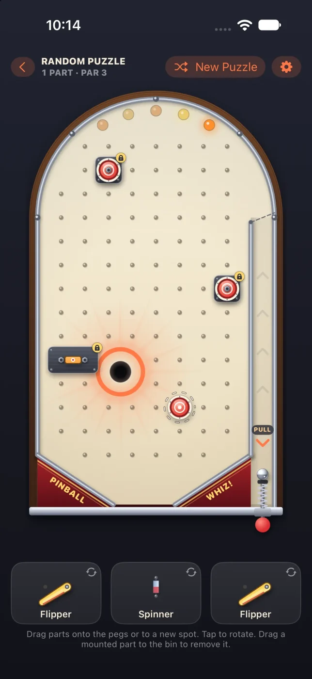 A Pinball Whiz! random puzzle on iPhone: a cream pinball table with locked bumpers, a glowing target hole, and a parts bin below holding two flippers and a spinner.
